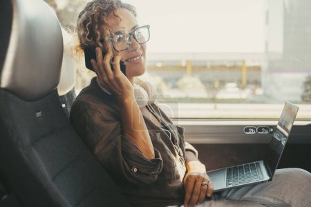 Foto de Communication and travel concept job lifestyle. Modern woman smile and using mobile phone sitting on a bus seat as a travel passenger. People and computer. Transportation and technology lifestyle - Imagen libre de derechos