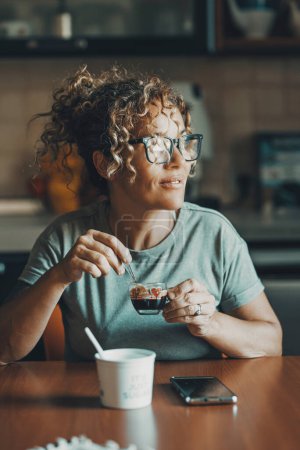 Téléchargez les photos : Femme buvant du café expresso italien à la maison seule assise dans la cuisine. Les gens et se réveiller petit déjeuner boisson. Les débuts. Nouvelle journée. Une femme à la table dans la cuisine à la maison - en image libre de droit