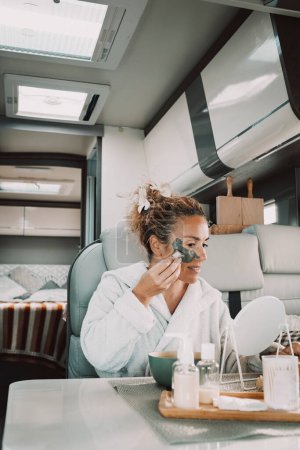Photo for Beauty mask application natural skin care treatment lifestyle for traveler female people living off grid inside a camper van. Interior view of motor home and vanlife concept woman. Wellbeing wellness - Royalty Free Image