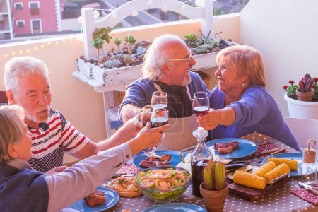 Photo for Love and relationship mature senior people celebrate and enjoy lunchtime all together outside at home. Holiday party retirement concept lifestyle. Happy couples mature having fun together toasting - Royalty Free Image