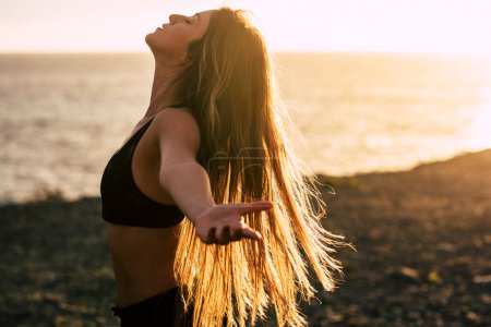 Photo for Sport and healthy people lifestyle concept. Side view of beautiful young woman opening arms and enjoying  outdoor health athlete daily leisure activity alone. Long hair and sunlight sunset light - Royalty Free Image