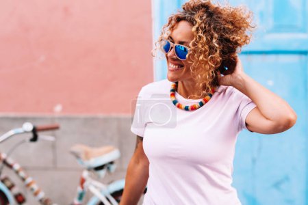 Photo for Portrait of cheerful young woman smiling and enjoying outdoor leisure activity outside home. Bike parked in background and house. Town healthy active lifestyle people. Beauty mature lady having fun - Royalty Free Image