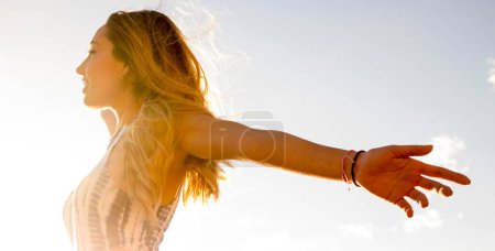 Photo for Success and happiness or freedom mindful concept lifestyle. Side view of young pretty girl opening arms outstretching against the sun. Healthy and joy mindset outdoor leisure activity alone. Travel - Royalty Free Image