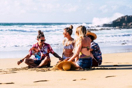 Téléchargez les photos : Groupe d'amis touristes profiter de l'été ludique activités de loisirs de plein air et vacances à la plage parler avec les filles et rire beaucoup ensemble dans l'amitié. - en image libre de droit