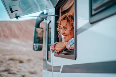Photo for One female tourist enjoy view and freedom feeling inside a camper van vehicle looking outside the window. Concept of nomadic life and vanlife independent modern people. New tiny house style. Transport - Royalty Free Image