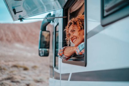 Photo for Travel and destination happiness concept lifestyle people. One serene woman smile and enjoy freedom and nature admiring outdoors inside her camper van motor home tiny house. Alternative lifestyle - Royalty Free Image