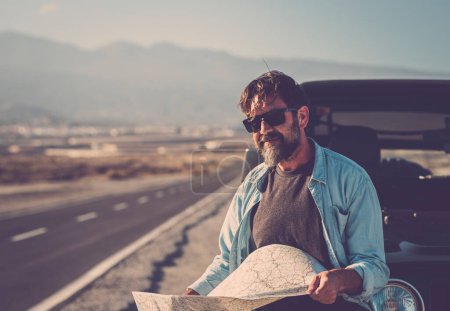 Photo for Travel transport people lifestyle. man looking the roads and using paper guide map to find destination and arrival time. Transportation. Summer car vacation driver. People and adventure lifestyle - Royalty Free Image