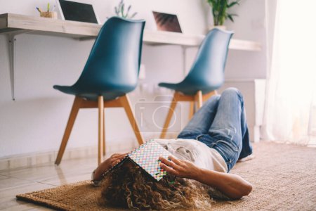 Photo for Woman at home lay down on the carpet, covering her face with a book. Concept of education and student middle age. Female people asleep on the floor in apartment. Tired and stressed lifestyle - Royalty Free Image