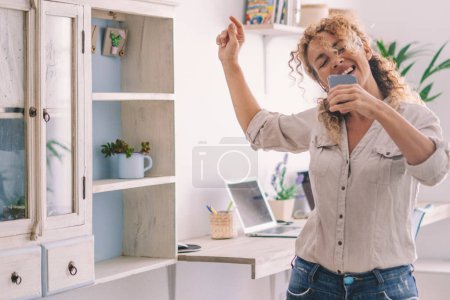 Photo for Overjoy and excited  lifestyle woman dancing and singing at home for happiness. Success and healthy lifestyle people in indoor leisure activity alone having fun with music and dance. Joyful - Royalty Free Image