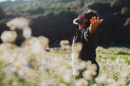 Téléchargez les photos : Homme ouvrant bras et amour parc naturel debout au milieu d'une fleur blanche fleurs étirant bras et profiter de la liberté et le bonheur émotion. Personnes conscientes et de destination de voyage en plein air - en image libre de droit
