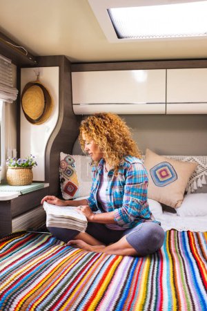 Photo for Vanlife and relax. Serene woman reading a book sitting on bed inside camper van bedroom. Relaxation and travel nomadic lifestyle people. Alternative cozy home motor home rv vehicle. Indoor leisure - Royalty Free Image
