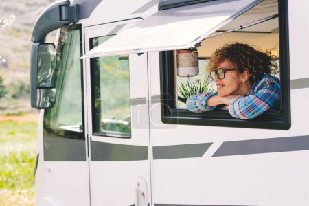 Photo for Happy tourist enjoy destination smiling outside the window of modern rented camper van motor home rv vehicle. Freedom and new normal alternative travel lifestyle people. Daydreaming woman journey life - Royalty Free Image