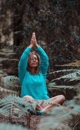 Photo for Wellbeing and meditate for healthy mindful lifestyle people.  woman in yoga meditation position sitting in the nature forest with green leaves and trees around her. Concept of health mind exercise - Royalty Free Image