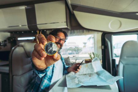 Photo for Travel and adventure people lifestyle.  man portrait showing compass and using road map paper to choose next trip destination. People and vehicle camper van interior. Van life off grid. Home vacation - Royalty Free Image