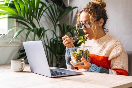 Foto de Gente sana estilo de vida y actividad ocupada negocio. mujer comiendo ensaladas frescas verdes frente a una computadora en la mesa en la oficina o en el lugar de la tarea. Concepto de cuerpo y cuidado mental. Alimento dietético - Imagen libre de derechos