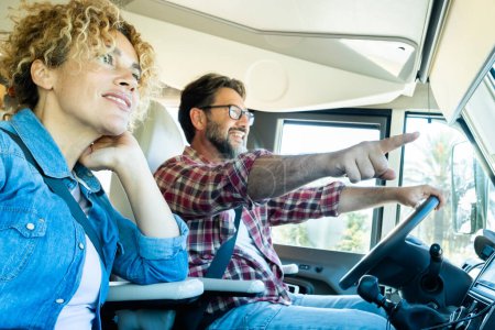 Photo for Happy couple of adult man and woman driving inside a camper van and enjoying alternative vehicle vacation together. Motor home travel lifestyle and vacation on the road. People living adventure trip - Royalty Free Image