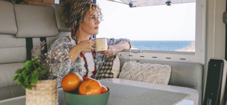 Photo for Traveler woman enjoy time and relax inside modern camper van with coffee - Royalty Free Image