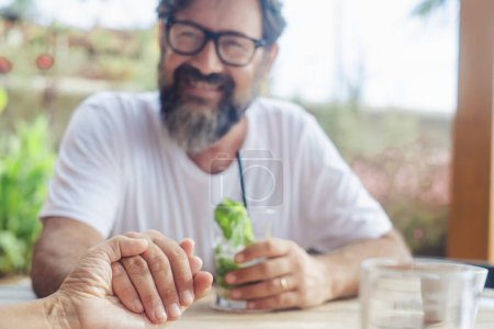 Photo for Happy man holding woman hand in pov. Focus on hands. Love and dating. Relationship adult people in love. Family on vacation sitting at the bar. Defocused background of male smiling having fun and wife - Royalty Free Image
