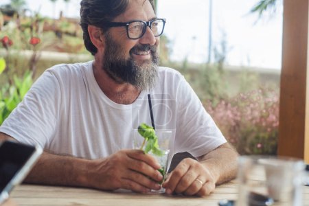 Photo for Portrait of serene happy adult man drinking mojito cocktail at the cafe bar in summer holiday vacation outdoor leisure activity. Tourist enjoying relax. One mature male smiling sitting at the table - Royalty Free Image