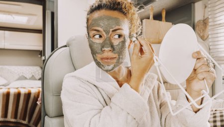 Photo for Close up portrait of  middle age woman putting natural skin care mask on her face and smile looking herself in a mirror. Happy concept lifestyle female people and beauty care treatment routine - Royalty Free Image