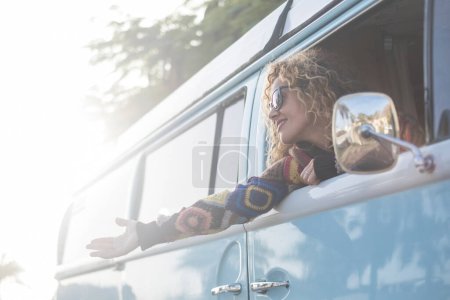 Photo for Travel and happiness. Freedom feeling enjoying life concept lifestyle people. woman traveling as a passenger inside a classic vintage van and have fun opening arms outside the windows. Vacation - Royalty Free Image
