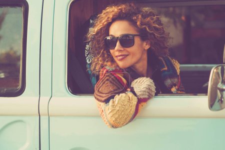 Téléchargez les photos : Les femmes voyagent avec un véhicule et regardent par la fenêtre en souriant et en appréciant le voyage seul. Concept de van classique location vacances gens tourisme style de vie. jolie mignon adulte femme passager - en image libre de droit