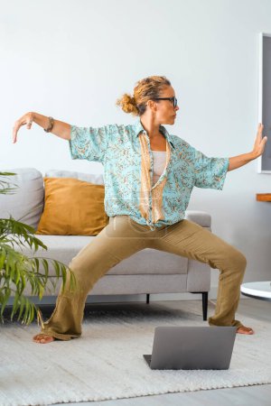 Photo for Woman in wellbeing indoor leisure activity, oriental exercises. Female stand up in living room and to tai chi exercise for total life balance life. People and zen like using online web page lesson - Royalty Free Image