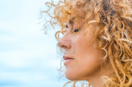 Photo for Close up side portrait of pretty adult woman with closed eyes and blonde natural healthy curly long hair. Concept of thinking and interior balance. Daydreamer outdoor female people enjoying nature - Royalty Free Image