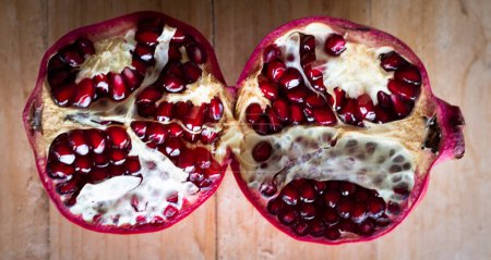 Photo for Pomegranate divided in two halves on a blue background viewed from above. Concept of winter and autumn months like october, november and December. Nature and fruit. Vitamins. Red color - Royalty Free Image