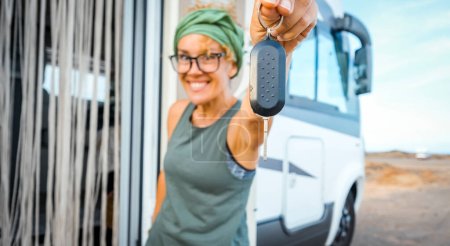Photo for Happy new buyer owner of camper van motorhome show at the camera her keys with happiness. New house and vehicle for vacation concept scene. Travel vanlife lifestyle. Adventure. Nomadic people female - Royalty Free Image