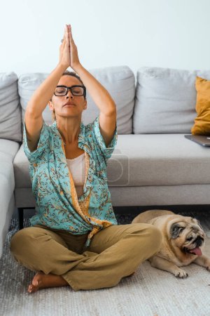 Foto de Bienestar femenino ocupado en yoga relajación rutina de salud en casa con el mejor amigo perro relajándose de su lado. Una mujer que hace ejercicio mental de salud y cambios corporales. Zen como ocio oriental - Imagen libre de derechos