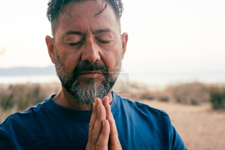 Photo for Man praying and meditate outdoor in relaxation gesture with hands clasped and closed eyes portrait. Zen like healthy mental balance lifestyle male people. Wellbeing. People zen exercise - Royalty Free Image