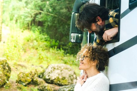 Photo for Happy camper van tourist tourism couple lifestyle. Man outside the motorhome window take care with sweetness of his wife woman outside enjoying nature and scenic arrival forest destination. People - Royalty Free Image