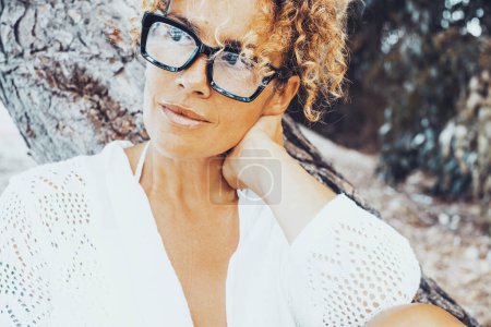Photo for Portrait of trendy fashion pretty attractive middle age woman in outdoor wearing black eyewear and looking on her side. Female people smile in outdoor relax leisure activity alone. Curly hair blonde - Royalty Free Image