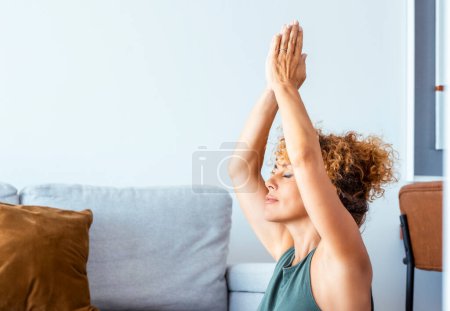 Téléchargez les photos : Femme adulte faisant des exercices de yoga à la maison seule dans le salon. Entraînement sain Pilates mode de vie personnes dans l'activité sportive intérieure. Bien-être et équilibre mental intérieur conscient femelle mature - en image libre de droit