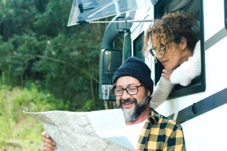 Photo for Happy travelers couple adult man and woman looking together a map guide to choose next destination. Vanlife and travel adventure vacation with camper van motor home modern vehicle lifestyle. Nature - Royalty Free Image