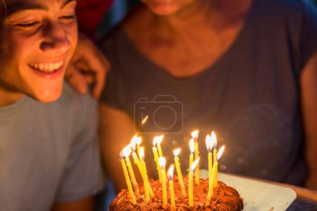 Foto de Primer plano de fiesta nocturna y pastel de cumpleaños con velas. Joven adolescente y abuelos disfrutan y celebran juntos con felicidad. Evento conceptual sobre la edad y el envejecimiento - Imagen libre de derechos