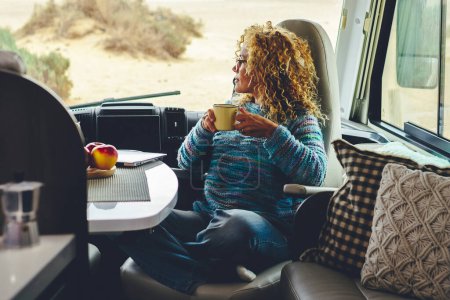 Téléchargez les photos : Femme adulte travaille sur un ordinateur portable assis dans un camping-car dinette profiter de vacances de voyage de liberté ou style de vie vanlife. Travail moderne avec la technologie de connexion informatique. Femmes freelance - en image libre de droit