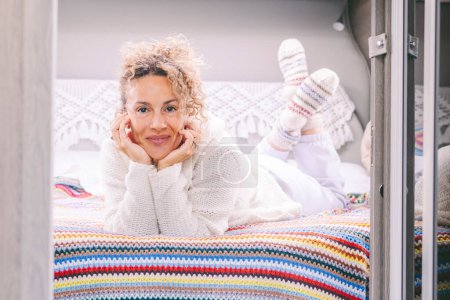 Photo for Portrait of cheerful, pretty adult woman laying and smiling inside her camper van in the bedroom. Concept of travel and living off grid people. Beautiful caucasian female lay on bed inside a motor home - Royalty Free Image