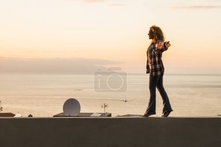 Foto de Mujer adulta de pie y caminando libre equilibrado con vista a la costa del océano en el fondo. Concepto de felicidad y estilo de vida libre para las mujeres independientes. Estilo de vida y viajes positivos - Imagen libre de derechos