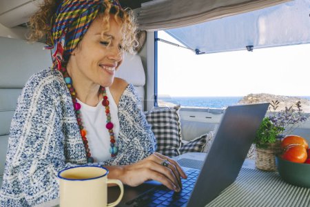 Photo for Modern woman work on laptop computer inside a camper van rv with ocean beautiful ocean view outside. Concept of online freedom job and smart working people. Digital nomad using connection - Royalty Free Image