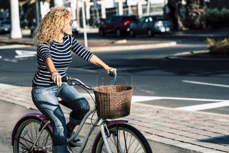 Photo for Adult woman use bike and take a ride in the town. People and outdoor leisure activity. Green transport alternative with bicycle. Modern female use and ride a bike in the street - Royalty Free Image