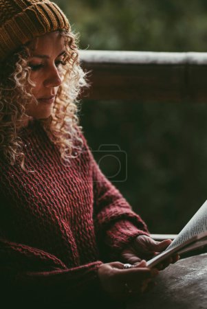 Foto de Relájese tiempo al aire libre en casa con mujer atractiva leyendo un libro con una luz de vela botella. Concepto de educación y ocio estilo de vida. Una mujer lee y estudia sola relajándose - Imagen libre de derechos