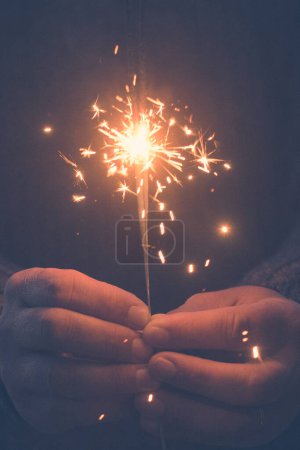 Téléchargez les photos : Image verticale de l'espace de copie des mains tenant un feu scintillant pour célébrer le Nouvel An ou Noël. Les gens ferment pour la fête et le plaisir des vacances. Liberté et espoir. Femme rêveuse - en image libre de droit