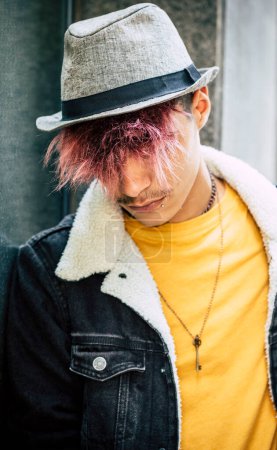 Photo for Sad and rebel teenager with alternative hair and casual clothes. Violet hairstyle for teenager with hat against a mirror in urban outdoor leisure activity alone. Concept of student and end of school - Royalty Free Image