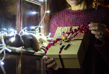 Téléchargez les photos : Fermer image bannière de cadeaux de Noël cadeau de partage. Femme déballage boîte de paperasse pour la nuit de Noël. Célébration des fêtes de décembre à la maison. Lumières au premier plan. Recevoir un cadeau surprise - en image libre de droit