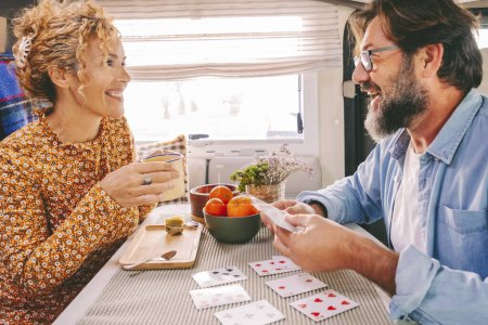 Photo for Happy couple enjoy time and have fun together inside camper van during travel lifestyle or holiday with vehicle. Man and woman playing cards with smile and joy.Indoor leisure activity people - Royalty Free Image