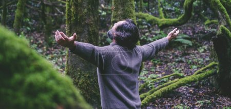 Téléchargez les photos : Un homme étendant les bras dans la forêt verte nature pour le bonheur et le bien-être état de santé mentale. Personnes et activités de loisirs de plein air. Bénéficiant planète Terre et destination de voyage. Le bonheur - en image libre de droit