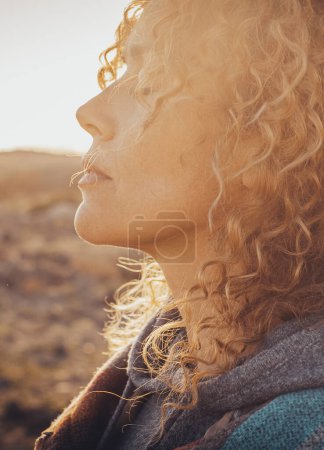 Photo for Side portrait of beautiful middle age blonde woman with long curly hair and closed eyes enjoying sunset in outdoors travel leisure activity alone. Wanderlust and interior balance happiness and freedom - Royalty Free Image