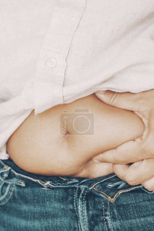 Téléchargez les photos : Woman holding belly fat abdominal with fingers hand. Concept of body acceptance and positivity. Diet and nutrition for healthy active lifestyle. Female people touching abdomen unhappy - en image libre de droit